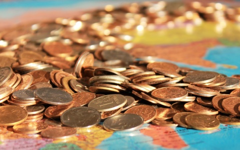 Das Bild zeigt Münzen die auf einer Landkarte liegen – symbolisch für das Geld, das an die Gewinner der Teuerung geht.