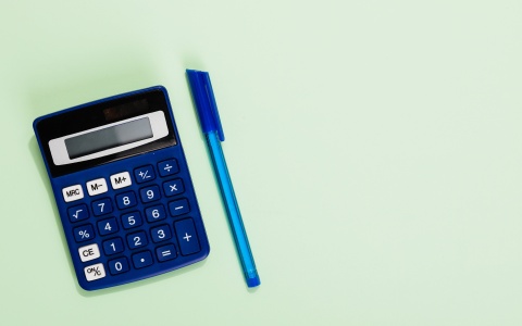 Blauer Taschenrechner und blauer Stift auf hellgrünem Hintergrund