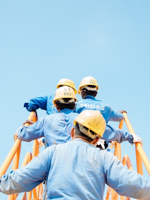 Bauarbeiter auf einer Leiter stehend vor blauem Himmel.
