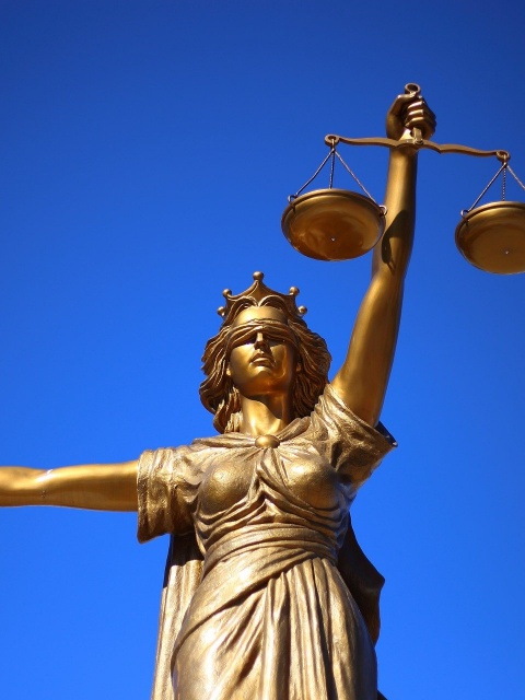 Statue Justicia gold mit blauem Hintergrund