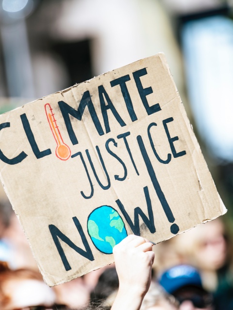 "Climate Justice Now" Schild als Symbol für eine ökosoziale Transformation gegen die Klimakrise