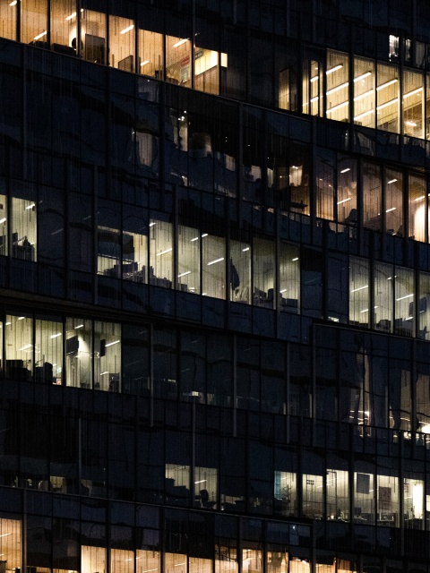 Bürogebäude in der Nacht mit beleuchteten Büros als Symbolbild für unbezahlte Überstunden