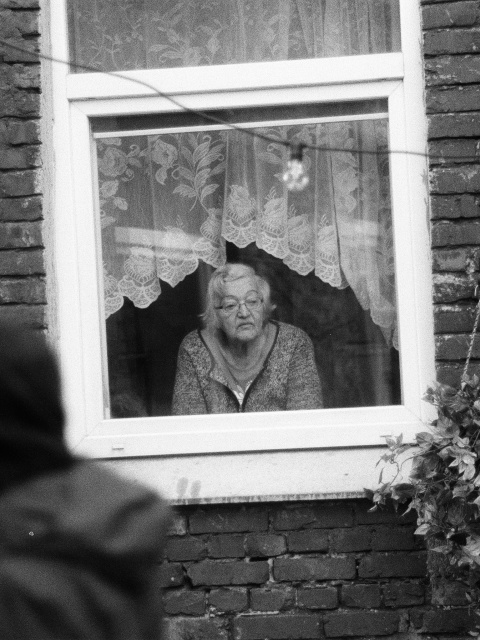 Alte Frau schaut aus dem Fenster – Symbolbild für den Equal Pension Day